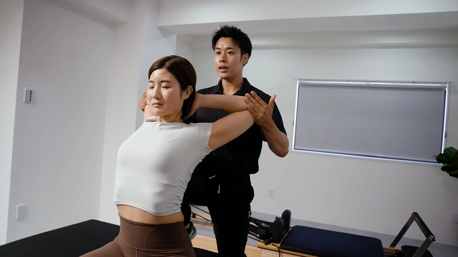 西武柳沢のストレッチメンテナンス専門店STLiNEで、トレーナーから肩まわりのパーソナルストレッチを受ける女性